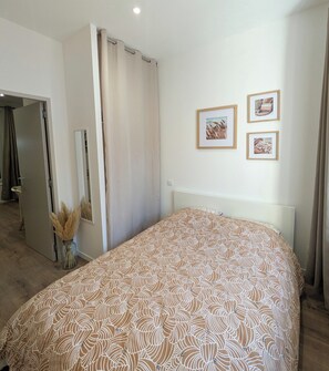 Een slaapkamer met een bed, een spiegel en twee afbeeldingen in een lijst aan de muur.