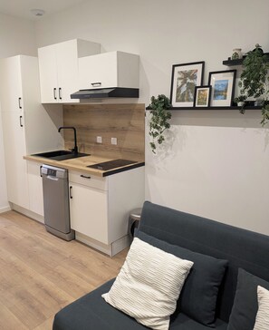 Een kleine keuken met witte kastjes, een vaatwasser en een houten aanrecht.