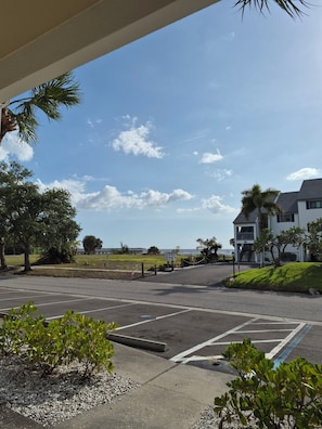 A parking lot with marked spaces, a building with a balcony, and a view of the ocean.