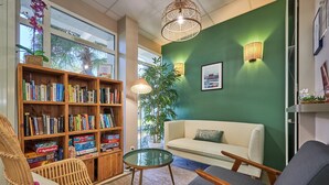 Una sala de estar acogedora con una estantería, una mesa redonda de vidrio, un sofá y un sillón.