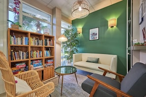A cozy living room with a bookshelf, a round glass coffee table, a sofa, and a chair. - Normandy Coastal Apartment for 5 (Courseulles-sur-Mer)