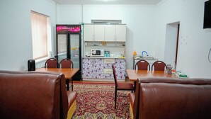 A compact living space with a dining area, kitchen, and a small seating area. - Meiman Guest House (Karakol)