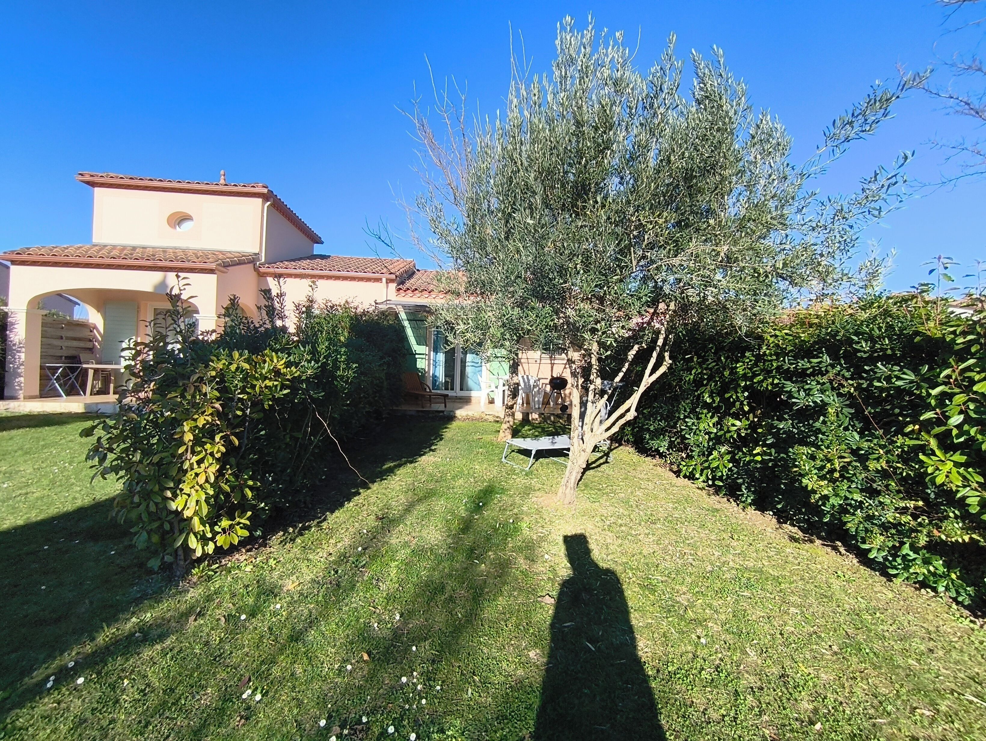 A house with a patio, a tree, and a clear blue sky.