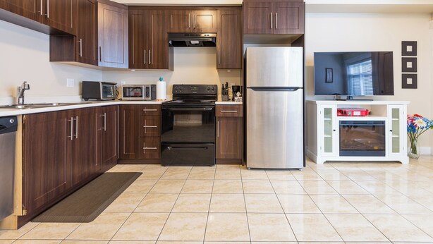 Una cocina moderna con armarios de madera oscura, electrodomésticos de acero inoxidable y piso de baldosas.