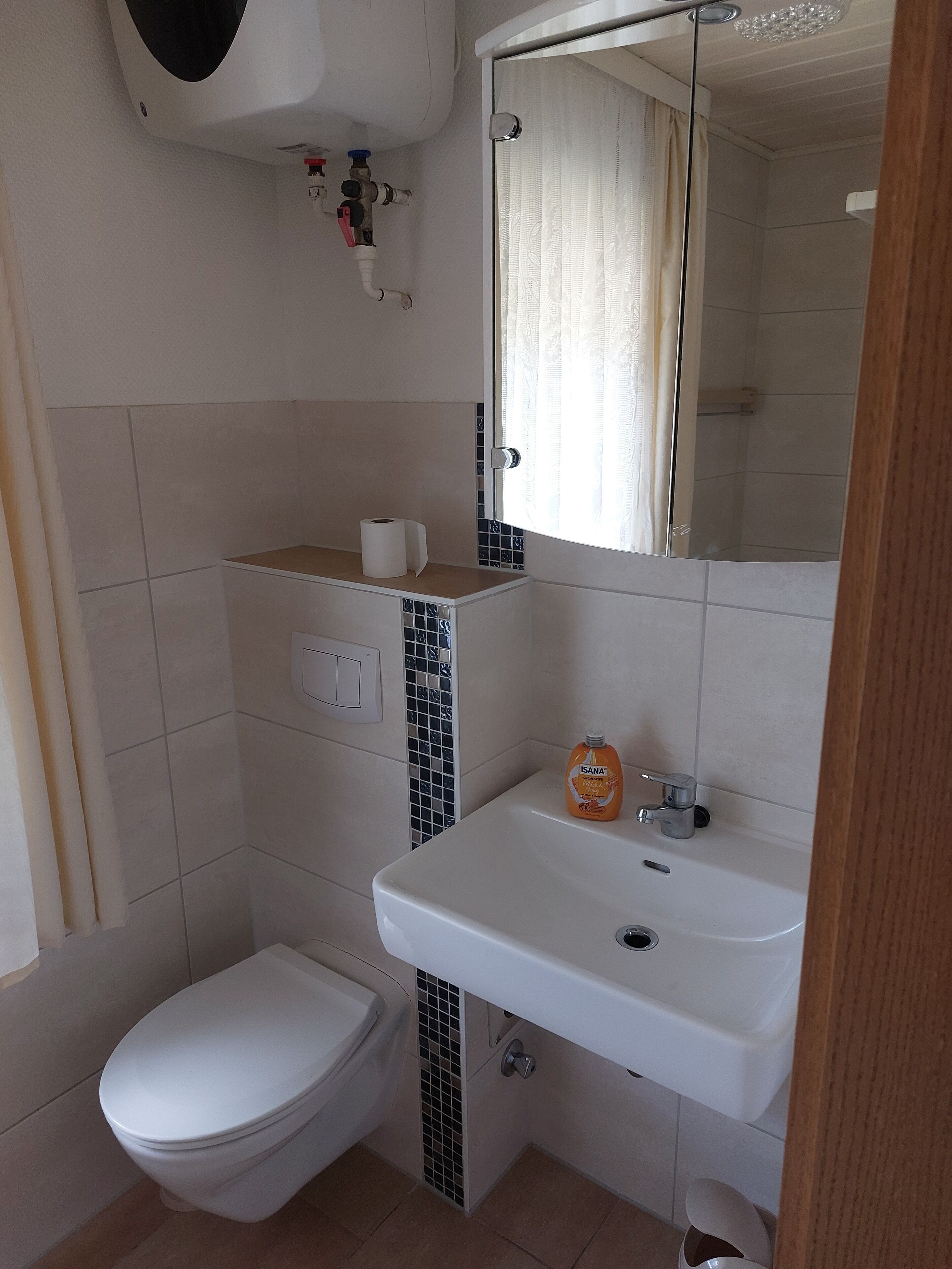 A bathroom with a toilet, sink, and mirror.