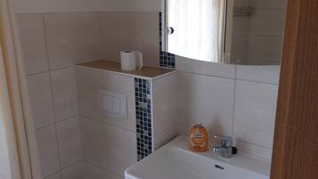 A bathroom with a toilet, sink, and mirror.