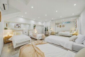 A modern hotel room with three beds, a large mirror, and a small desk area. - Nordic Bliss Marbella Townhouse (Marbella)