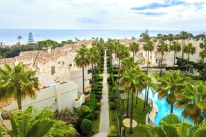 A resort with a pool, palm trees, and a view of the sea. - Nordic Bliss Marbella Townhouse (Marbella)
