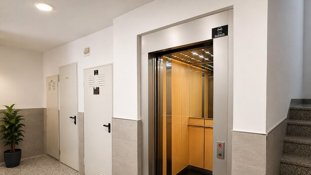 Un ascensor con panel de control, una planta en maceta y una escalera.