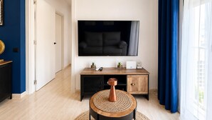 Una sala de estar moderna con un televisor de pantalla plana, una mesa de centro de madera y una cortina azul.