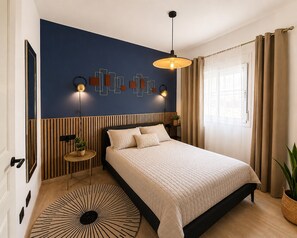A modern bedroom with a bed, a wall-mounted light fixture, a round rug, and a window with curtains. - Apartment for 3 Near the Beach (Roquetas de Mar)