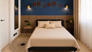 Un dormitorio con cama, mesitas de noche, una lámpara de pared, un espejo y una ventana con cortinas.