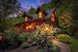A log cabin with a porch and a well-maintained garden. - Romantic Cabin * Sauna * Hot tub * King Suite (Sevierville)