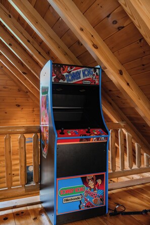 A Nintendo arcade machine in a wooden room with sloped ceilings. - Romantic Cabin * Sauna * Hot tub * King Suite (Sevierville)