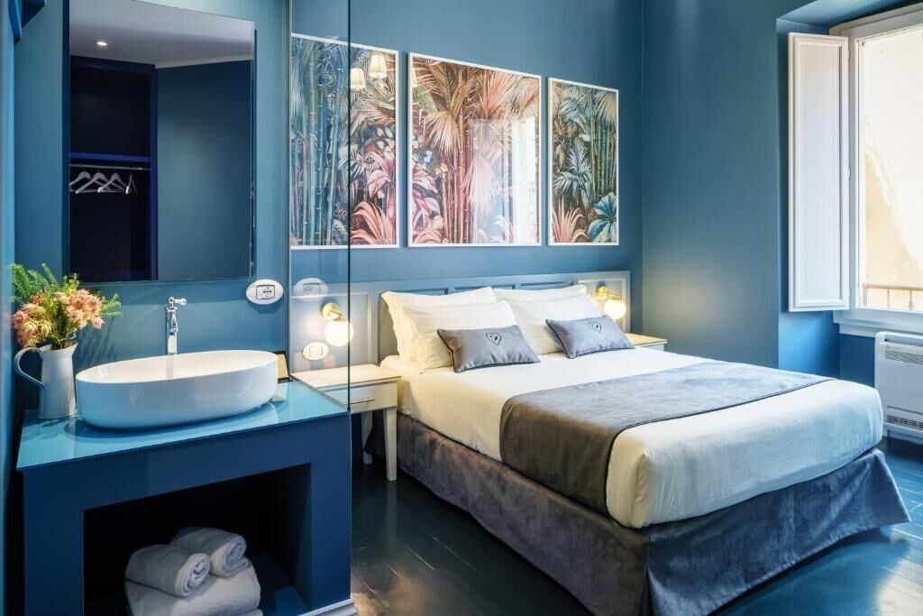 A modern bedroom with a large bed, a bedside table, a built-in sink, and a mirror.