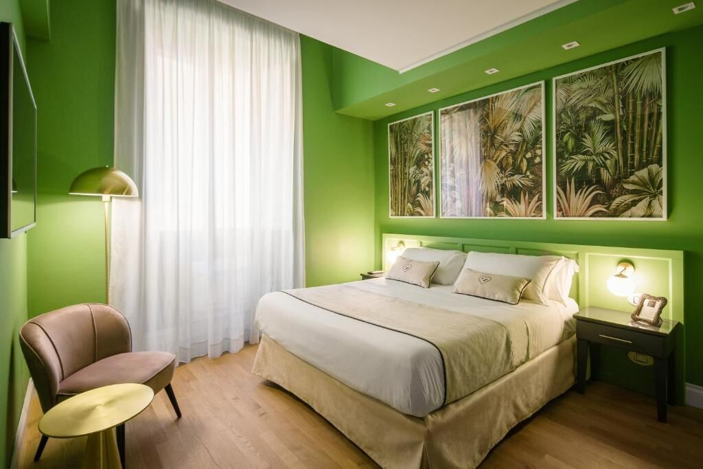 Een slaapkamer met een bed, een stoel, een nachtkastje en een muur met drie ingelijste foto's.