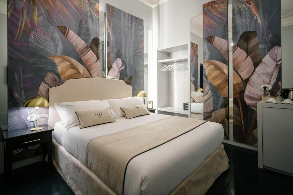 Een moderne hotelkamer met een groot bed, nachtkastje, bureau en garderobe.