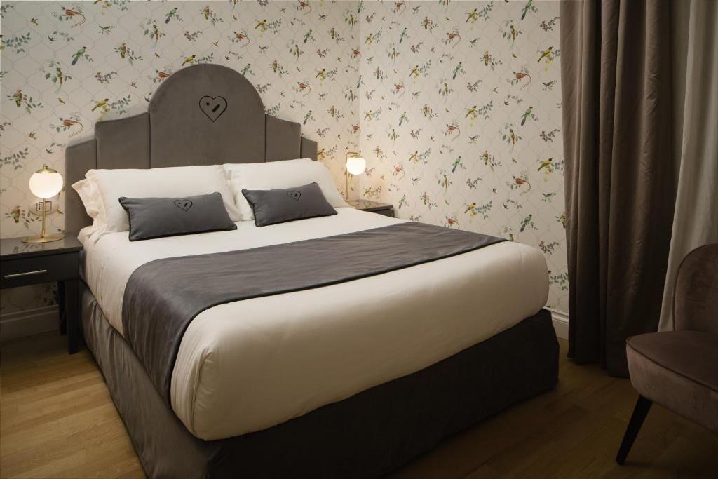 Een slaapkamer met een bed, nachtkastjes, een stoel en bloemenbehang.