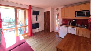 Een compact woongedeelte met een kitchenette, een eethoek en een grote schuifdeur naar buiten.