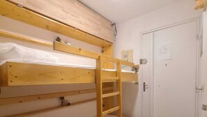 Een slaapkamer met een stapelbed, een ladder, een deur en een lamp.