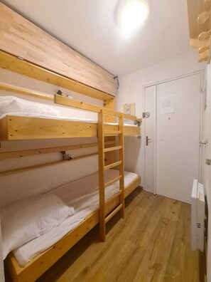 Ein Mehrbettzimmer mit einer Himmelsleiter, einer Tür und einer Leuchte.