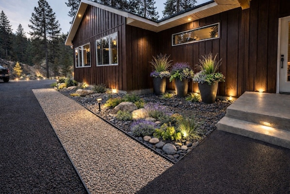 A modern house with a wooden exterior, a gravel pathway, and potted plants.