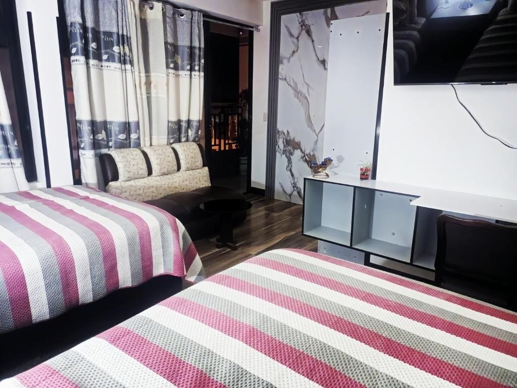 Una habitación de hotel con cama, sofá, televisor y pared de mármol.