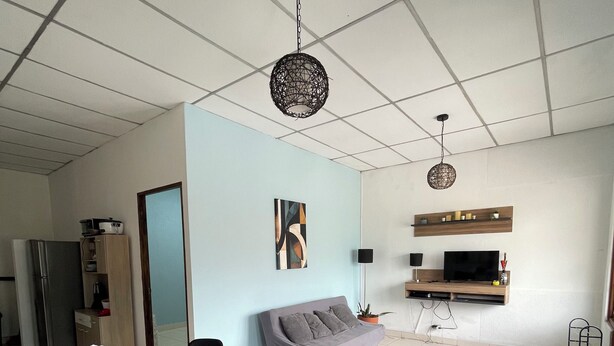 En moderne stue med spiseplads, sofa, fjernsyn og et loft med et gittermønster.