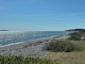 Ein felsiger Strand mit freiem Blick auf das Meer und das entfernte Land.