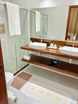 A bathroom with two sinks, a mirror, a glass shower enclosure, and a toilet. - Arraial d'Ajuda House with Private Pool (Arraial d'Ajuda)