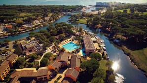 Ett flygbildsbild av ett semesterområde med en swimmingpool, en småbåtshamn och omgivande grönska.