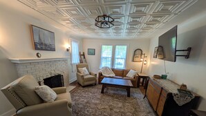 A living room with a fireplace, a sofa, a coffee table, and a TV. - Beautiful 4-bedroom historic home on 4-acre lot in Niles, close to Hwy 12 (Niles)
