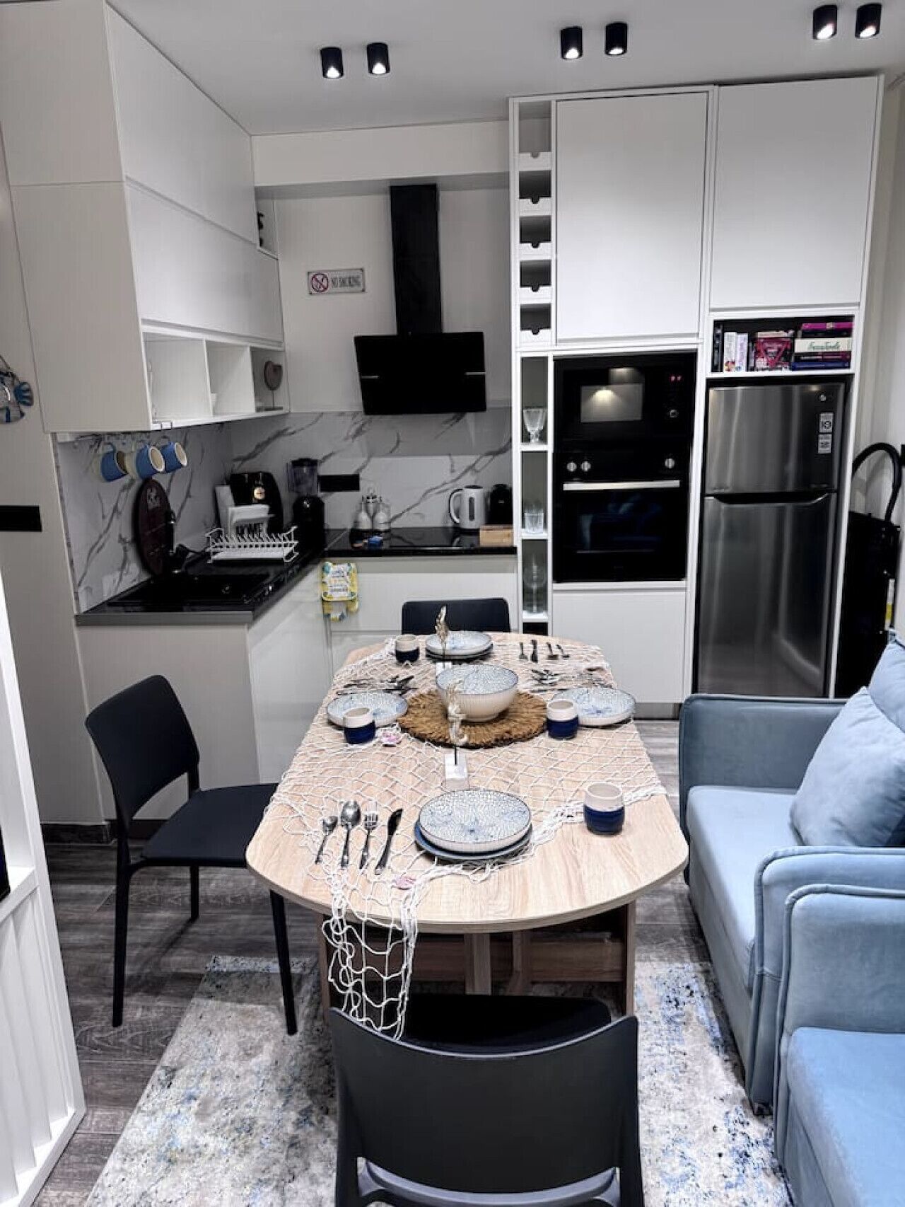 A compact kitchen with a dining table set for four, a built-in oven, and a refrigerator.