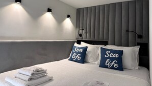 A modern hotel room with a bed, two wall-mounted lights, and a headboard with vertical panels. - Sea Dream Studio Qerret (Golem)