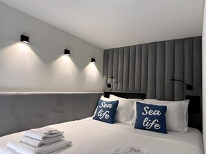A modern hotel room with a bed, two wall-mounted lights, and a headboard with vertical panels. - Sea Dream Studio Qerret (Golem)