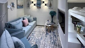 A modern living room with a grey sofa, a patterned rug, wall-mounted lights, and a fireplace. - Sea Dream Studio Qerret (Golem)