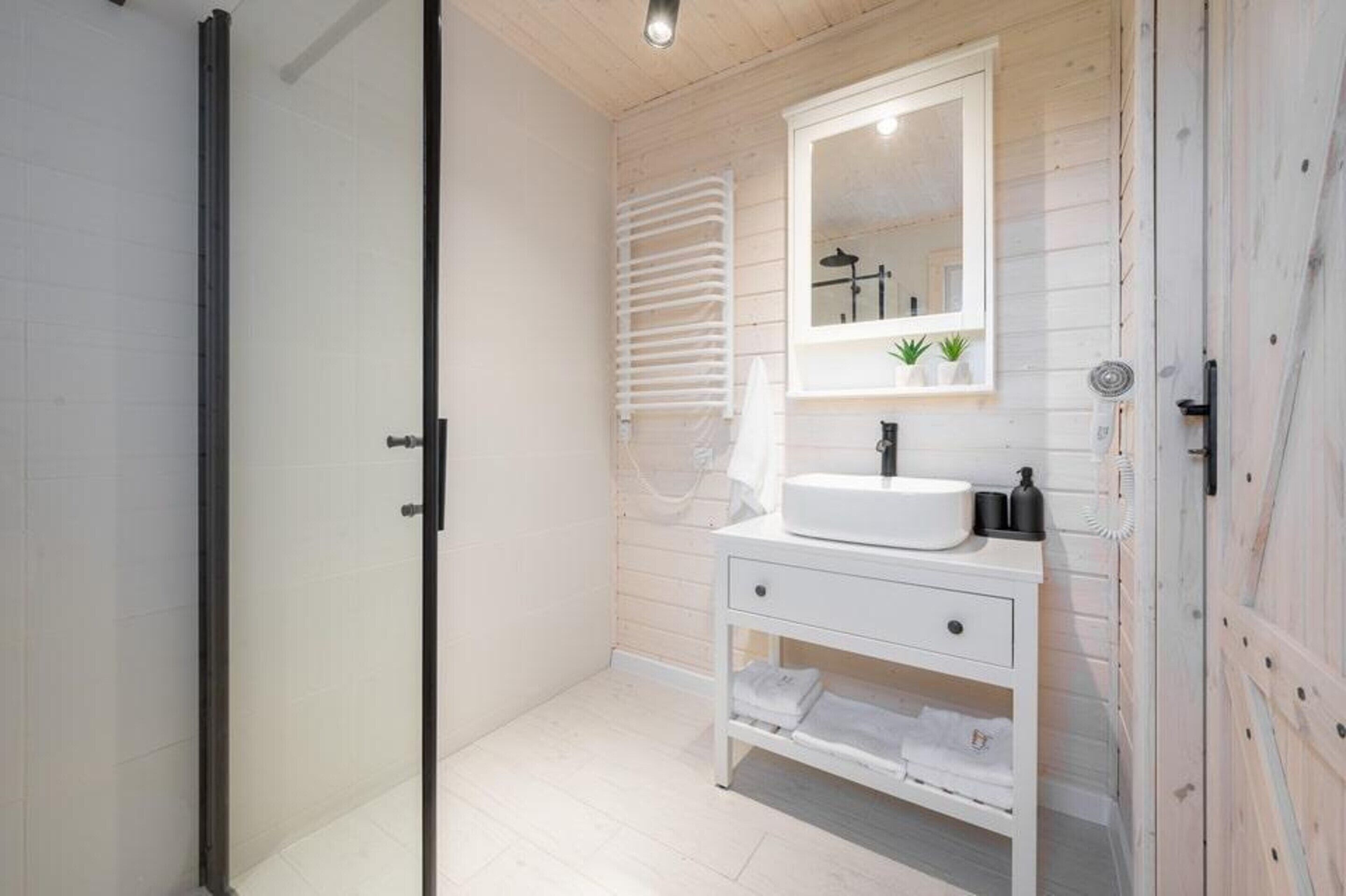 A modern bathroom with a white vanity, a large mirror, and a towel rack.