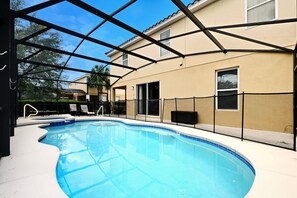A swimming pool with a covered area, a patio with chairs, and a building in the background. - Spacious modern home w/ private arcade, pool and spa (Davenport)
