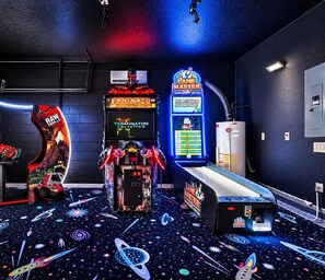 A gaming room with arcade machines, a neon sign, and a space-themed floor. - Spacious modern home w/ private arcade, pool and spa (Davenport)
