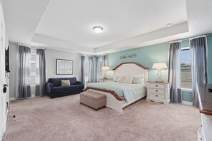 Ein Schlafzimmer mit einem großen Bett, einem Nachttisch, einer Kommode, einer Bank und einem Sofa.
