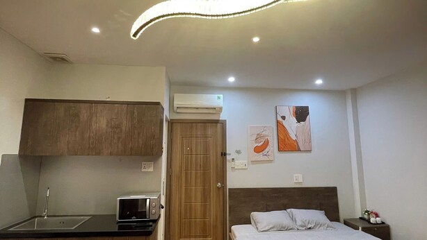 Quarto de hotel compacto com cozinha compacta, uma cama e um pequeno espaço de estar.