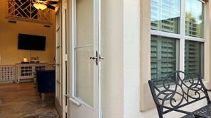 Ein Zimmer mit einer Schiebetür, einem Fernseher, einem Schrank und einer Bank.
