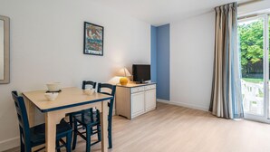 A room with a dining table, chairs, a television, and a cabinet. - Stunning Oceanfront Haven for 2 (Île-aux-Moines)
