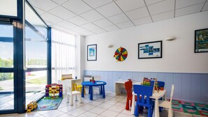 A children's playroom with a large window, colorful play tables, and chairs. - Stunning Oceanfront Haven for 2 (Île-aux-Moines)