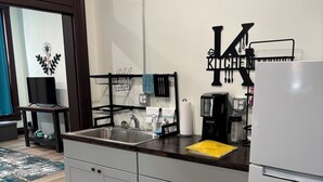 Ett modernt kök med en diskho i rostfritt stål, en kaffebryggare och ett kylskåp.