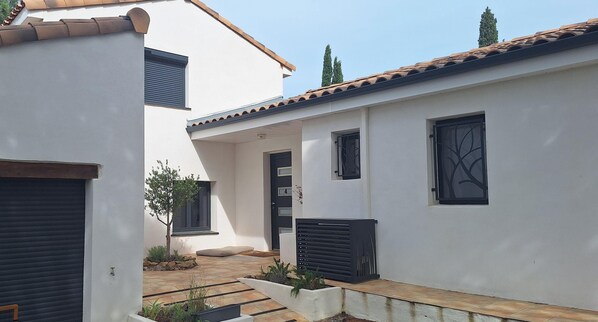 A courtyard with a white building, a black door, and a small tree. - Between the sea and the mountains, a quiet independent room with a view! (Neffiès)