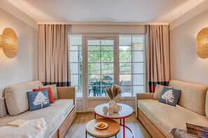 A room with a sofa, a small table, and a window with curtains. - Stunning Landes Pine Apartment for 5 (Biscarrosse)