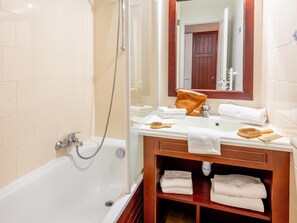 A bathroom with a bathtub, a shower, a vanity with a mirror, and a shelf with towels. - Stunning Landes Pine Apartment for 5 (Biscarrosse)