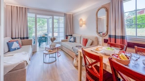 Una sala de estar con sofá, mesa de comedor, sillas y vista a través del ventanal.