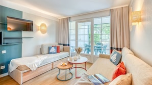 Una sala de estar moderna con un sofá, un sillón adicional, una mesa de centro y un televisor montado en la pared.